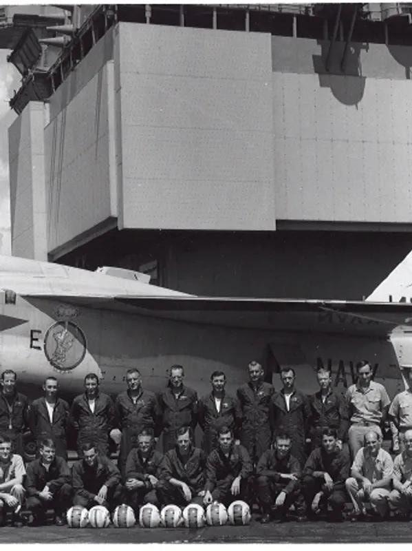 Navy crew posed in front of aircraft on carrier deck